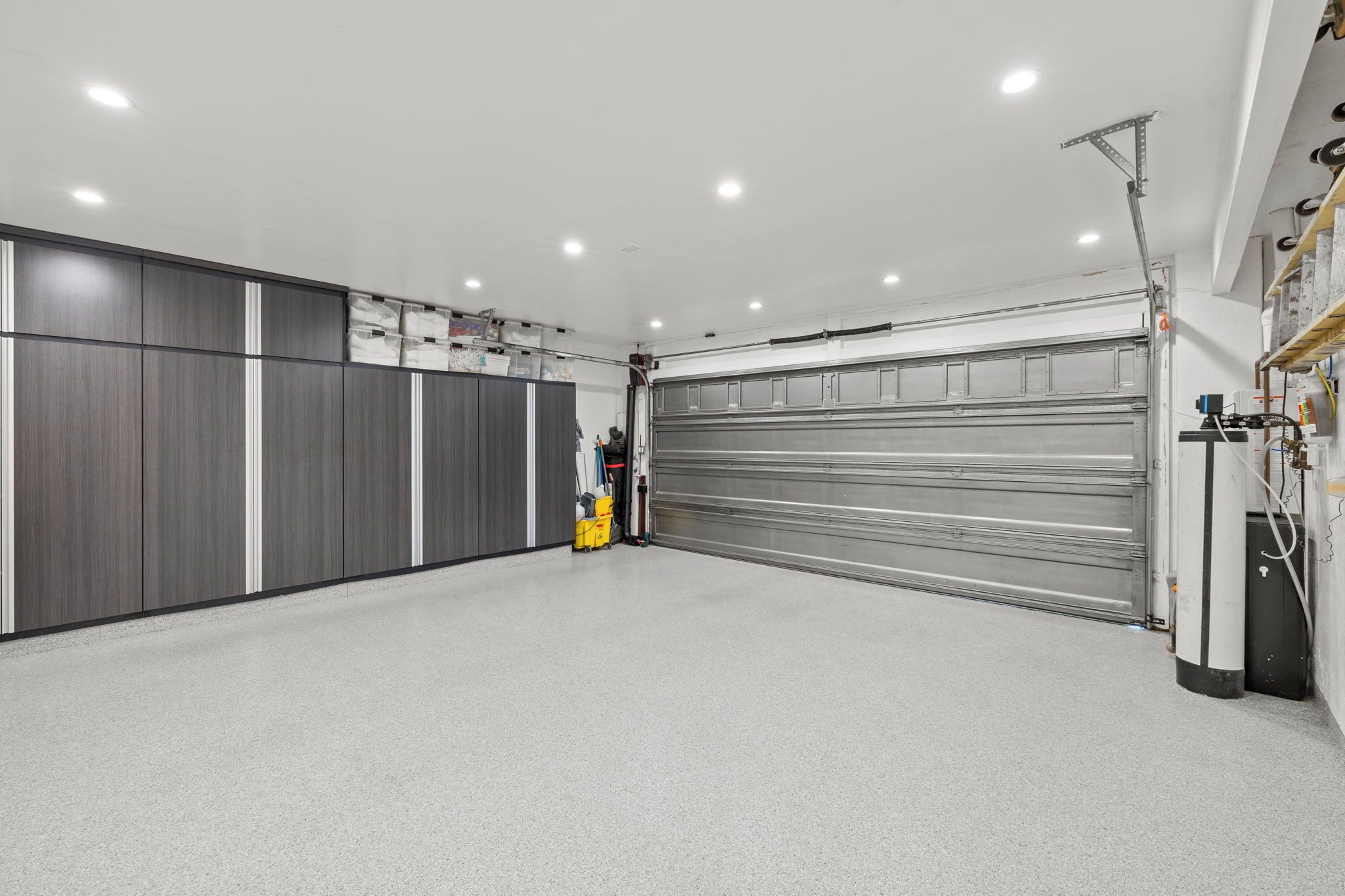 Een garage met een grote metalen deur, opslagkasten en een werkbank.