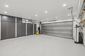 Un garage doté d’une grande porte métallique, de placards de rangement et d’un établi.