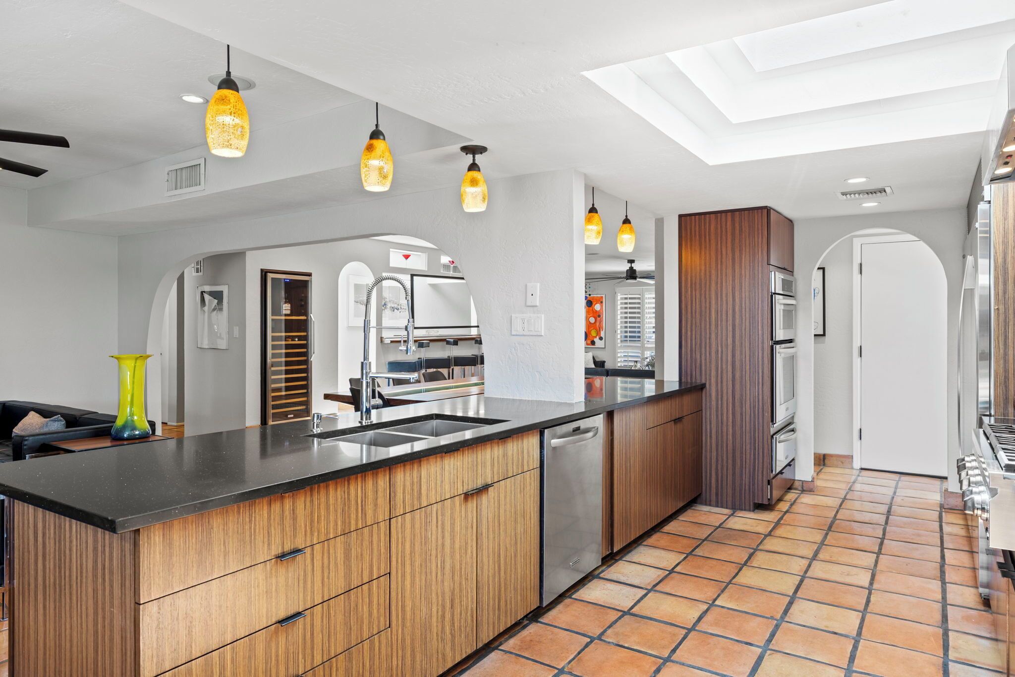 Una cocina moderna con una isla central, electrodomésticos de acero inoxidable e iluminación colgante.