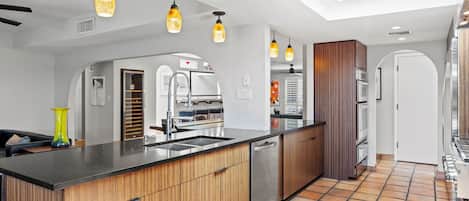 Una cocina moderna con una isla central, electrodomésticos de acero inoxidable e iluminación colgante.