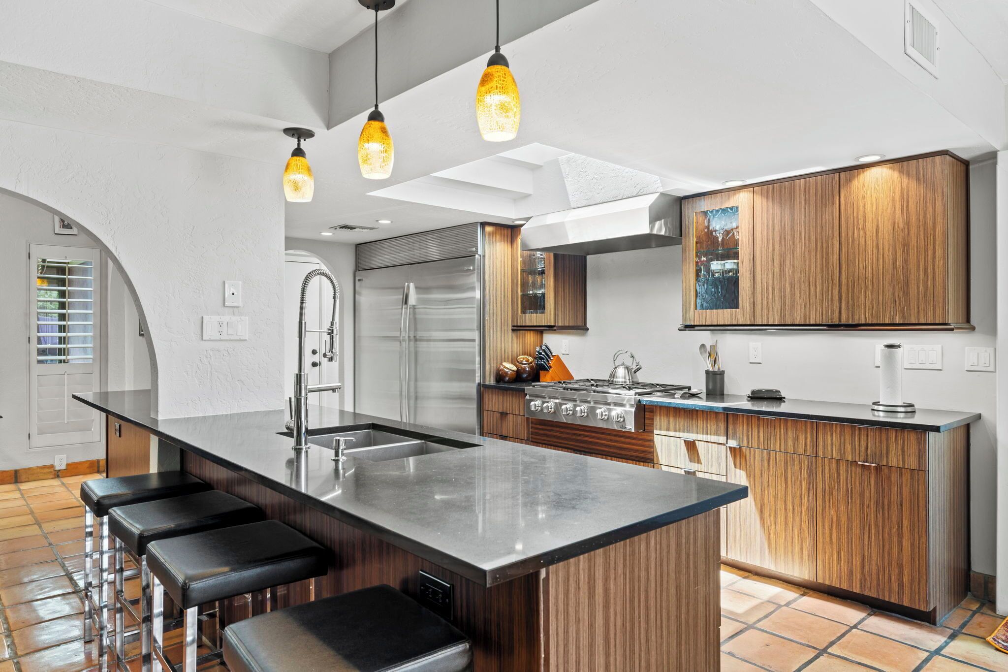 A modern kitchen with a central island, stainless steel appliances, and wooden cabinetry.