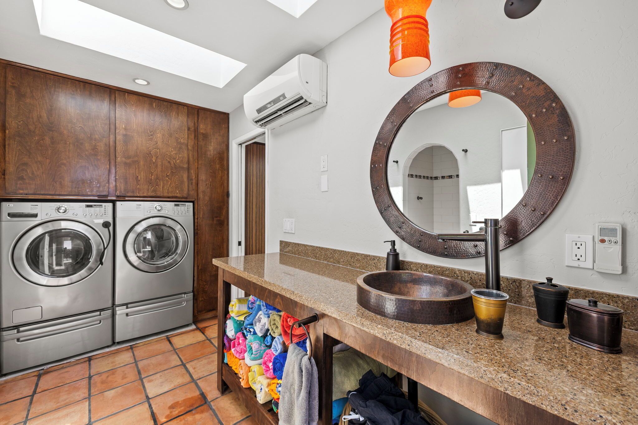 A modern bathroom with a large mirror, a sink, and two wall-mounted washing machines.