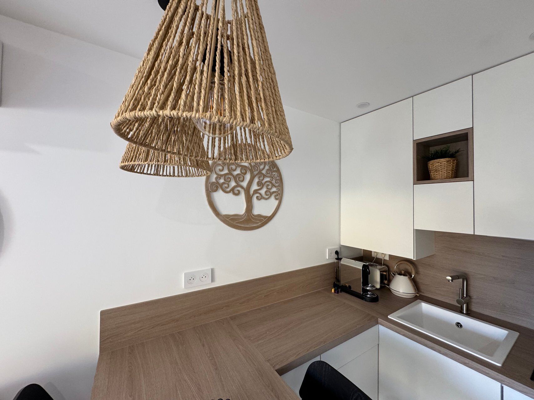 Een moderne keuken met een houten aanrecht, een ingebouwde gootsteen en een hangende lamp.