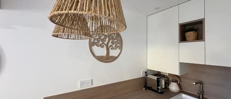 A modern kitchen with a wooden countertop, a built-in sink, and a hanging light fixture.
