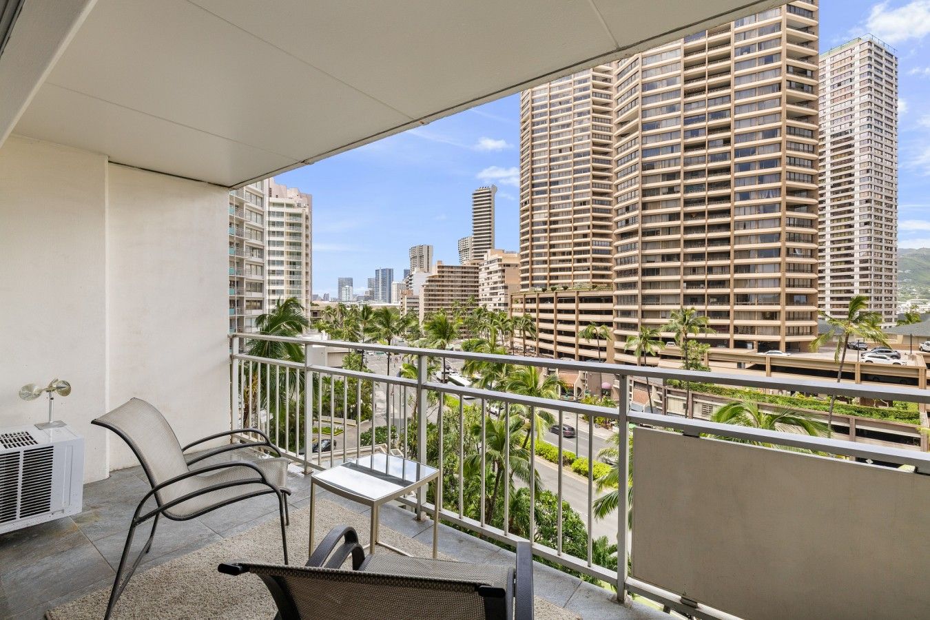 A balcony with a view of high-rise buildings, a table, and two chairs.