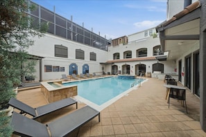 A pool area with lounge chairs, a hot tub, and outdoor seating. - Modern 2BR Apartment with Pool, Gym & Free Parking (Houston)