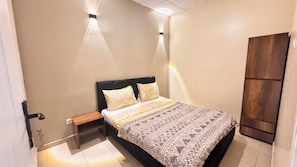 Un dormitorio con cama, mesitas de noche y un armario.