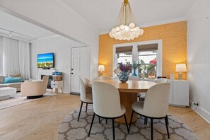 A modern living room with a dining area, a television, and a large window. - Two-home tropical retreat near Palm Beach Zoo (West Palm Beach)