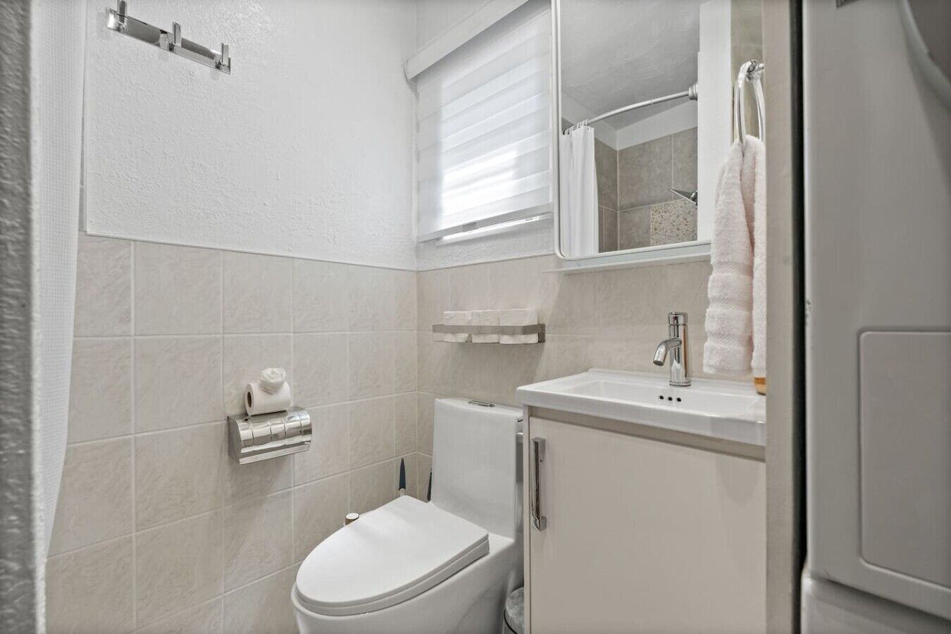 A bathroom with a toilet, a sink, and a mirror.