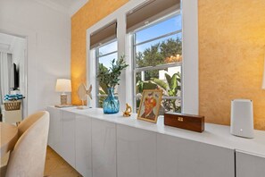 A room with a white cabinet, a lamp, a vase with plants, a framed picture, and a speaker. - Two-home tropical retreat near Palm Beach Zoo (West Palm Beach)