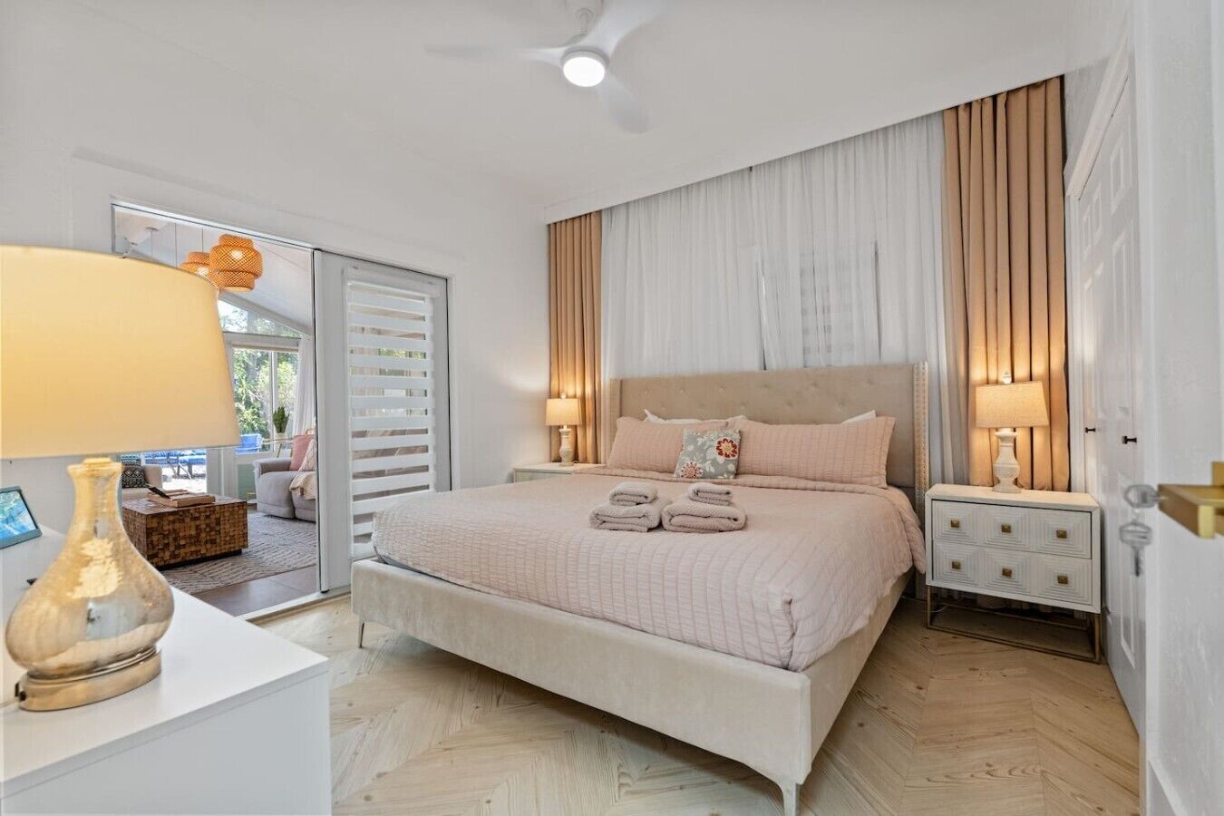 A bedroom with a bed, bedside tables, a lamp, and a view through a sliding door.