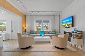 A modern living room with a fireplace, a television, and a view of the outdoors. - Two-home tropical retreat near Palm Beach Zoo (West Palm Beach)