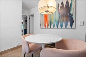 Een eethoek met een ronde tafel, twee stoelen en een moderne hanglamp.