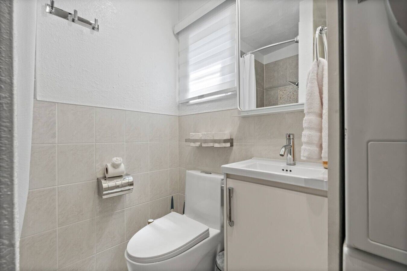 A bathroom with a toilet, a sink, and a mirror.