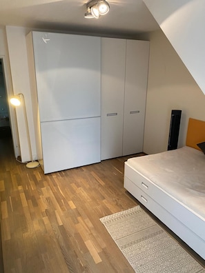A bedroom with a bed, a wardrobe, a floor lamp, and a patterned rug. - Comfortable 3 Bedroom within walking distance to Stadt Park Hilton. (Vienna)