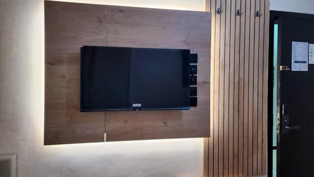Televisor de pantalla plana montado en una pared de madera con iluminación integrada.