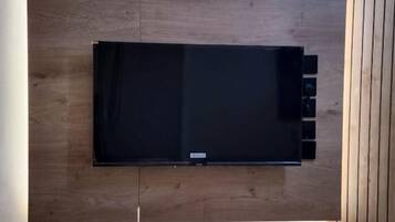 A flat-screen TV mounted on a wooden wall with a wooden panel to the right.