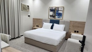 Una habitación de hotel con cama, mesitas de noche, escritorio y una silla.