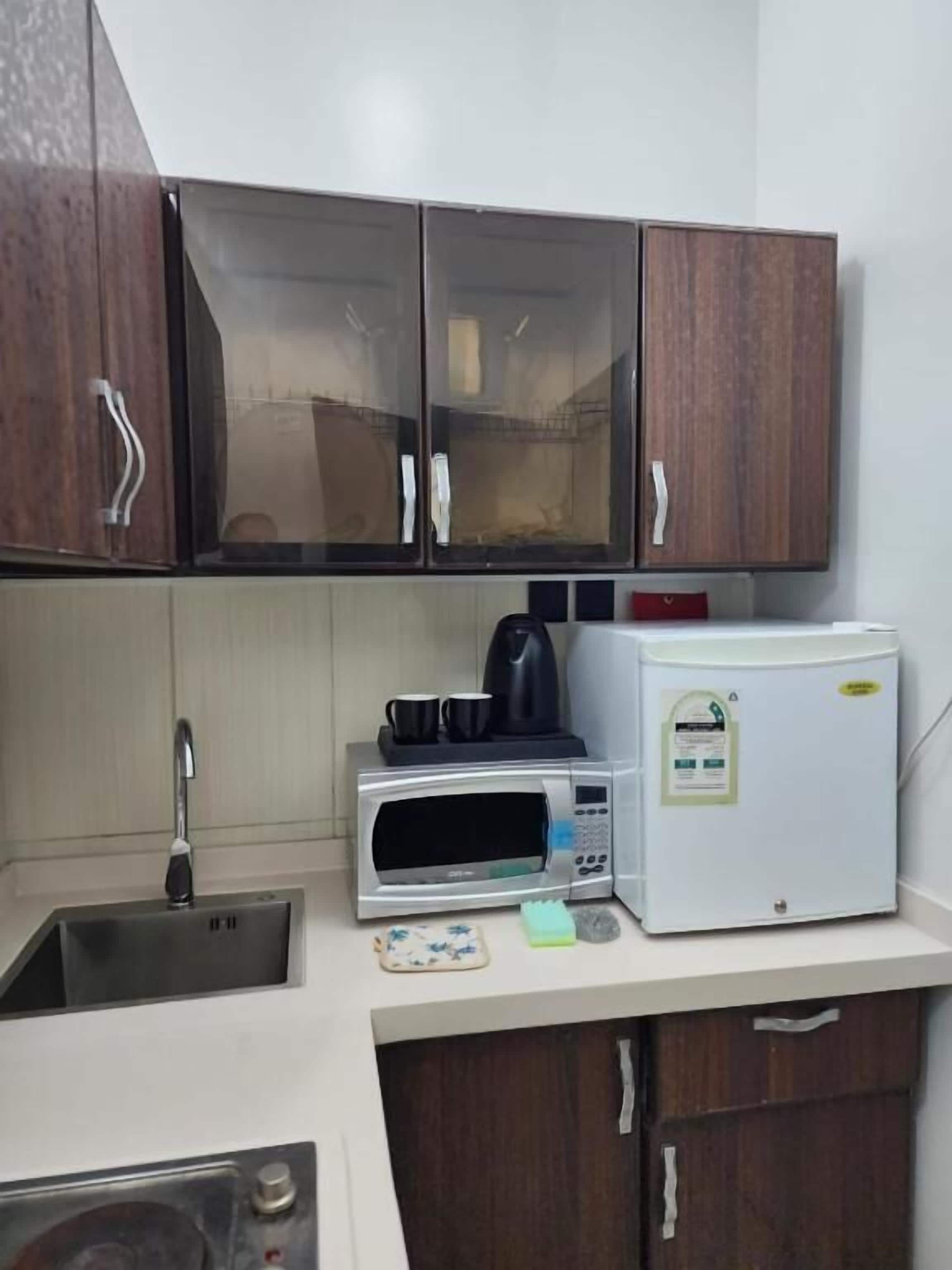 Uma cozinha compacta com micro-ondas, cafeteira e geladeira.