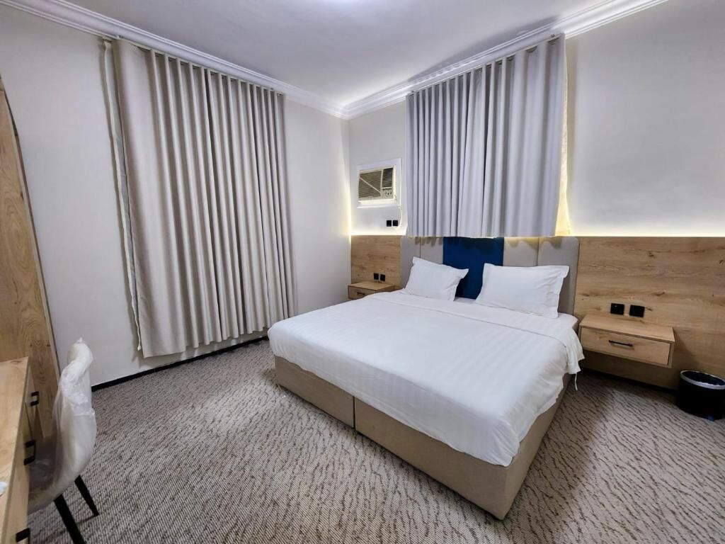 Et hotelværelse med en stor seng, sengeborde, et skrivebord og en stol.