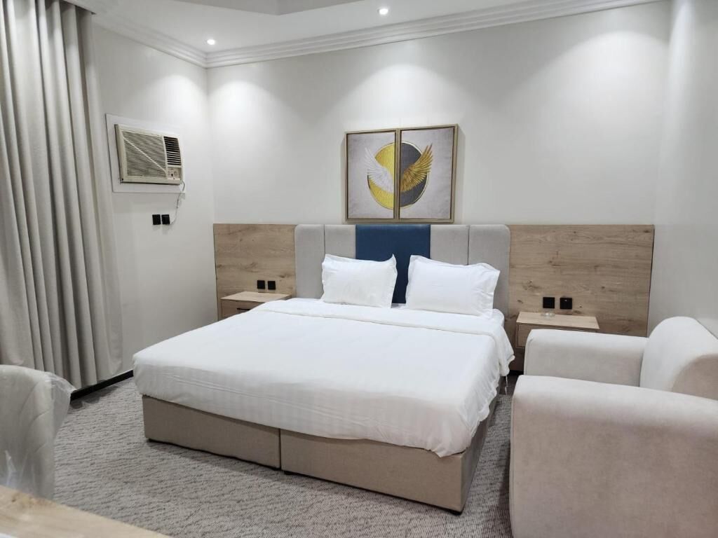 Un dormitorio moderno con una cama grande, mesitas de noche y un aire acondicionado de pared.