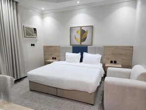 Un dormitorio moderno con una cama grande, mesitas de noche y un aire acondicionado de pared.