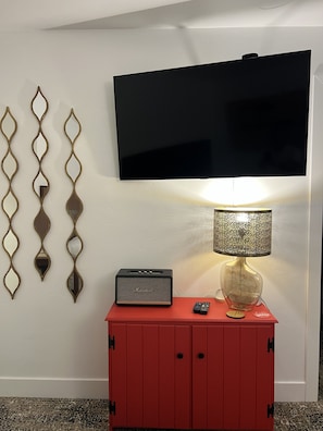 A room with a flat-screen TV mounted on the wall, a red cabinet with a radio and remote control, and decorative wall mirrors. - Townhome with Mount Massive, Massive View! (Leadville)