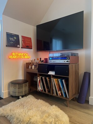 A living room with a flat-screen TV mounted on the wall, a vinyl record player, and a collection of vinyl records on shelves. - Townhome with Mount Massive, Massive View! (Leadville)