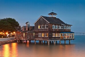Ein Holzhau mit mehreren Terrassen, die über Wasser hinausragen, mit großen Fenstern und einem markanten Turm.