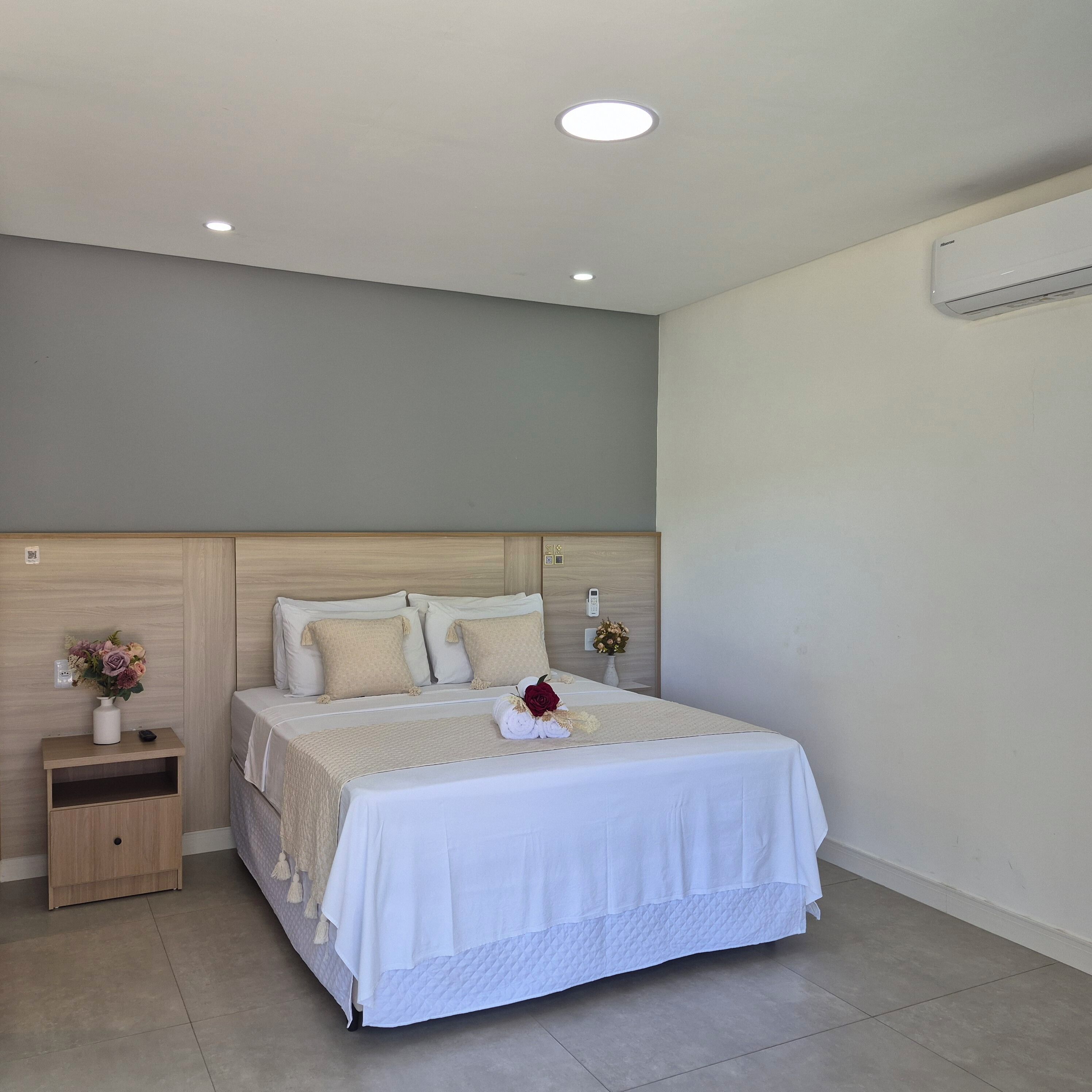 A neatly arranged bedroom with a bed, bedside tables, and a wall-mounted air conditioner.