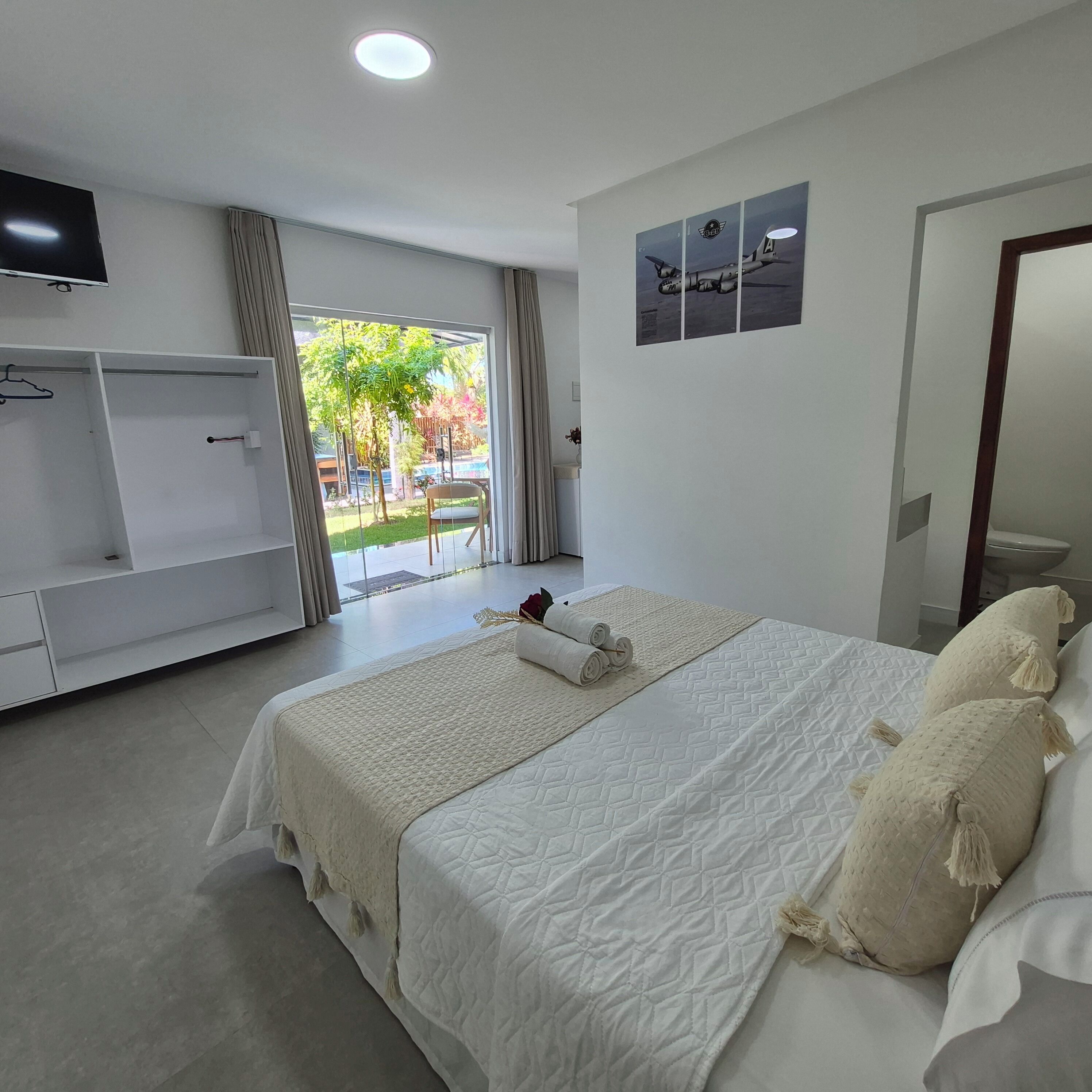 Una camera d'albergo con un letto, una TV, un armadio e vista sull'esterno.