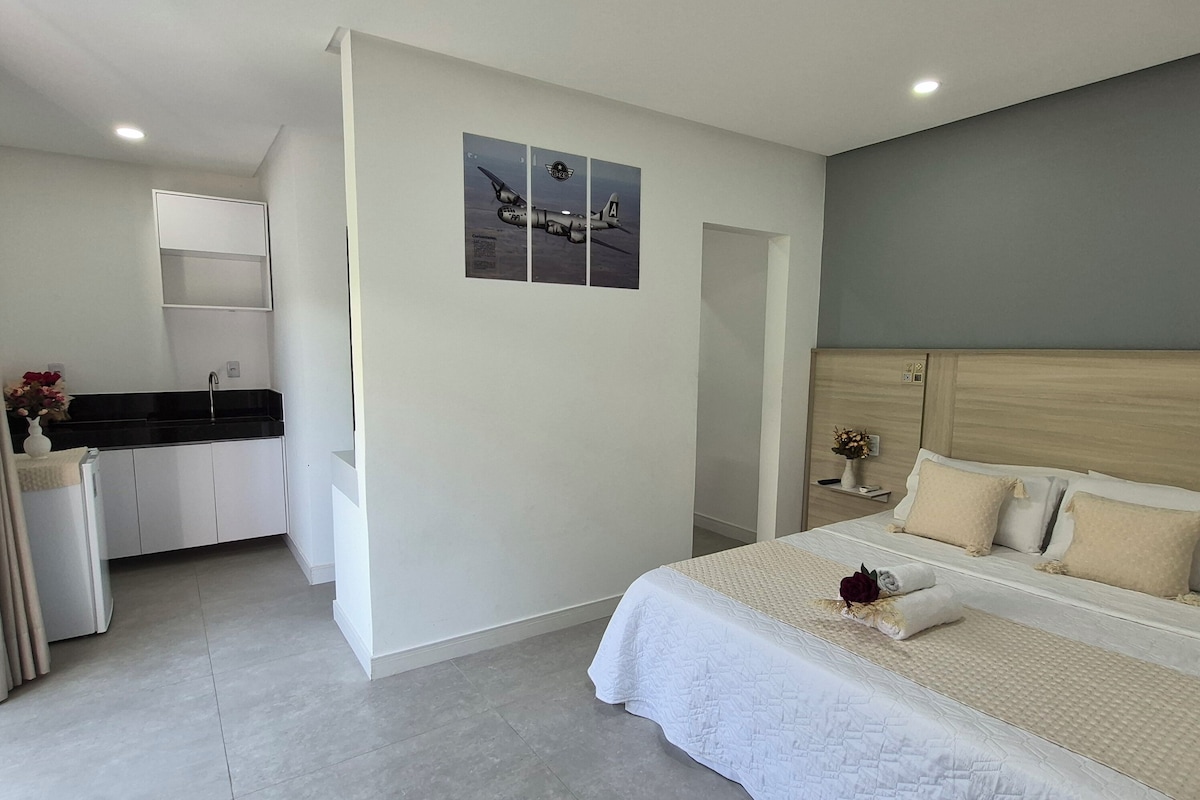 Quarto moderno com uma cama grande, uma kitchenette pequena e um banheiro.