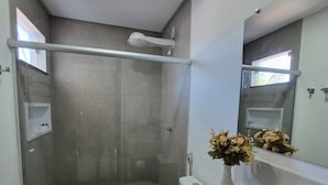 Un baño moderno con ducha a ras de suelo, inodoro y zona de lavamanos.