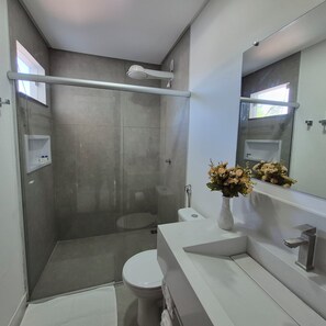 Ein modernes Badezimmer mit begehbarer Dusche, Toilette und Waschtisch.