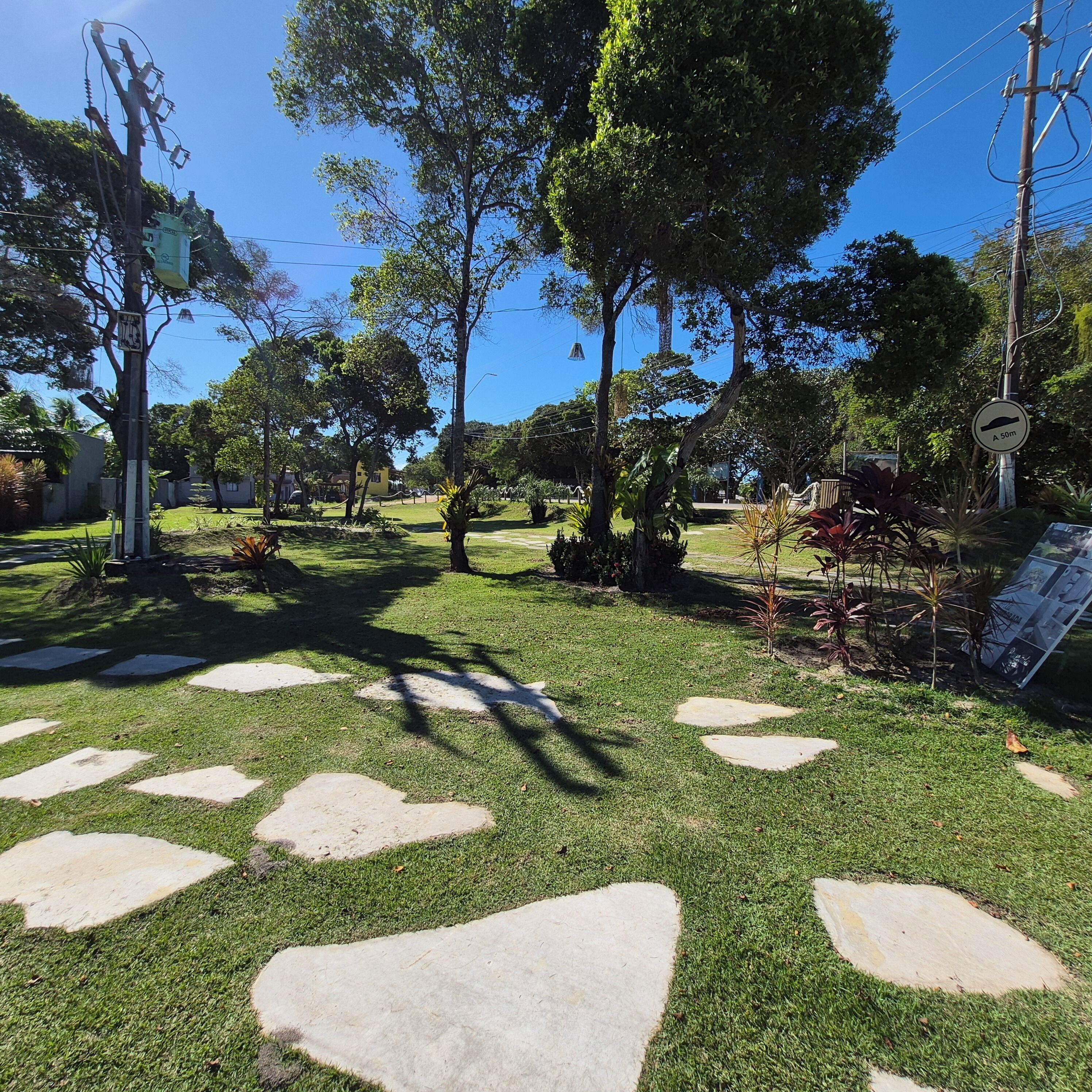 A well-maintained garden with stone pathways, lush greenery, and a clear sky.