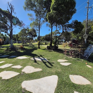 Un jardin bien entretenu, avec des allées pavées de pierres, une végétation luxuriante et un ciel dégagé.