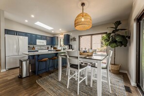 Una cocina moderna con una isla central, muebles blancos y un colgador de techo.
