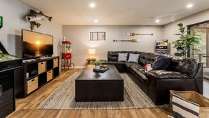 Ein modernes Wohnzimmer mit einem Ledersofa, einem Couchtisch, einem Fernseher und einem Spieltisch.