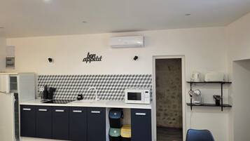 A modern kitchen with a microwave, sink, and cabinets, and a dining area with a table and chairs.