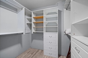 Et walk-in closet med åbne hylder, skuffer og plads til ophængning.
