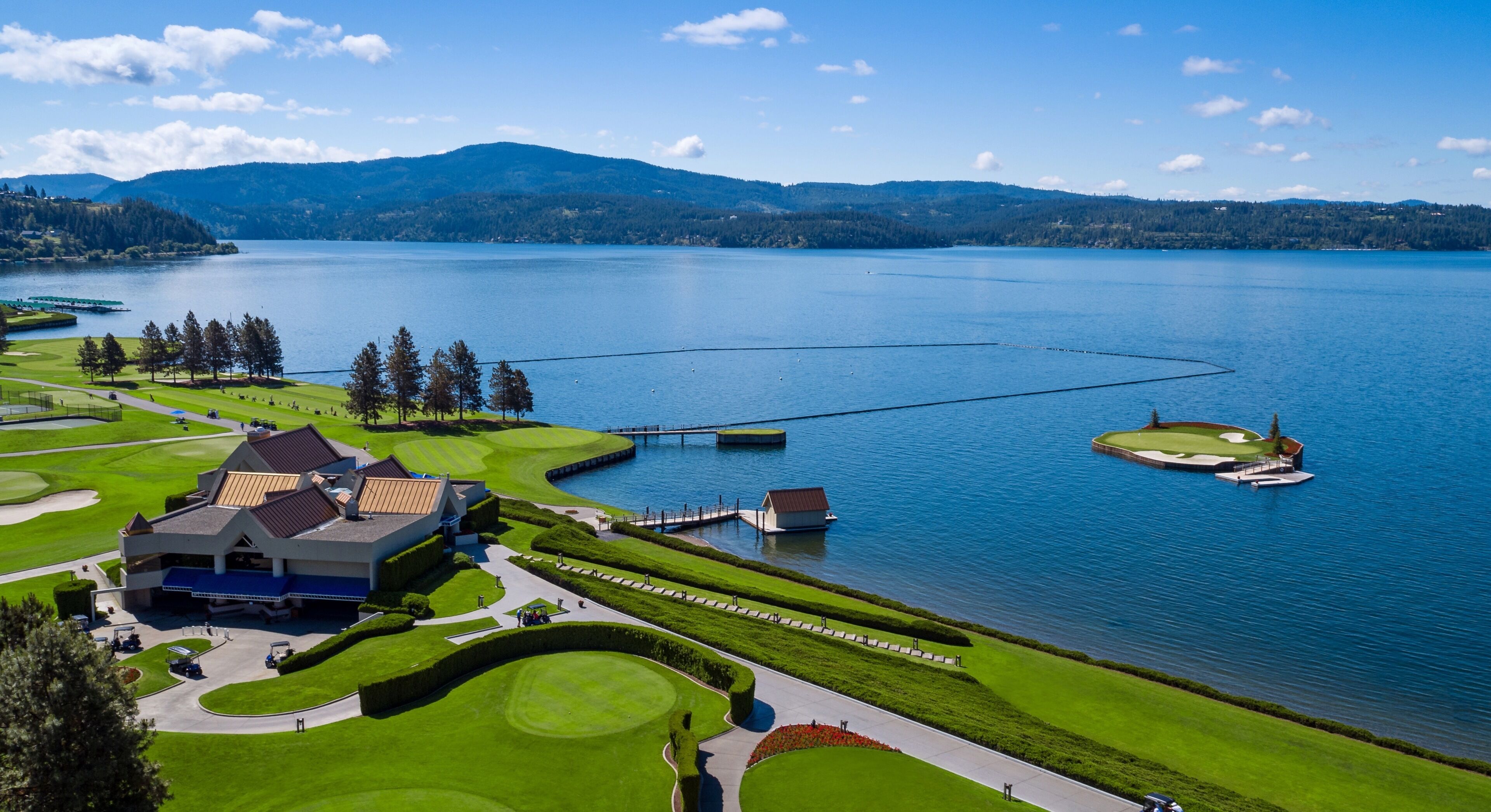 Een golfbaan met een clubhuis, een steiger en een groot waterlichaam.
