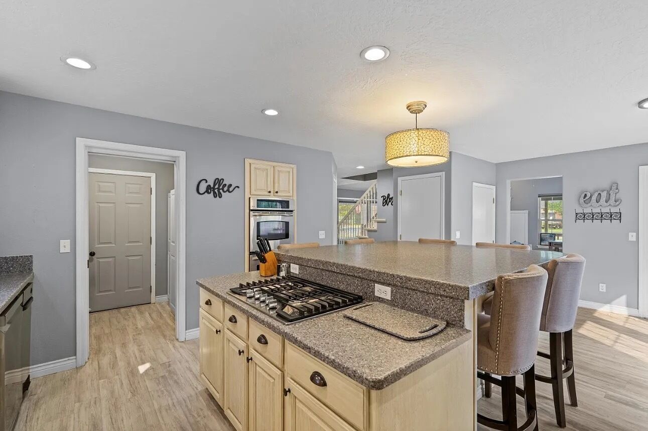 A kitchen with a central island, built-in appliances, and a dining area with bar stools.
