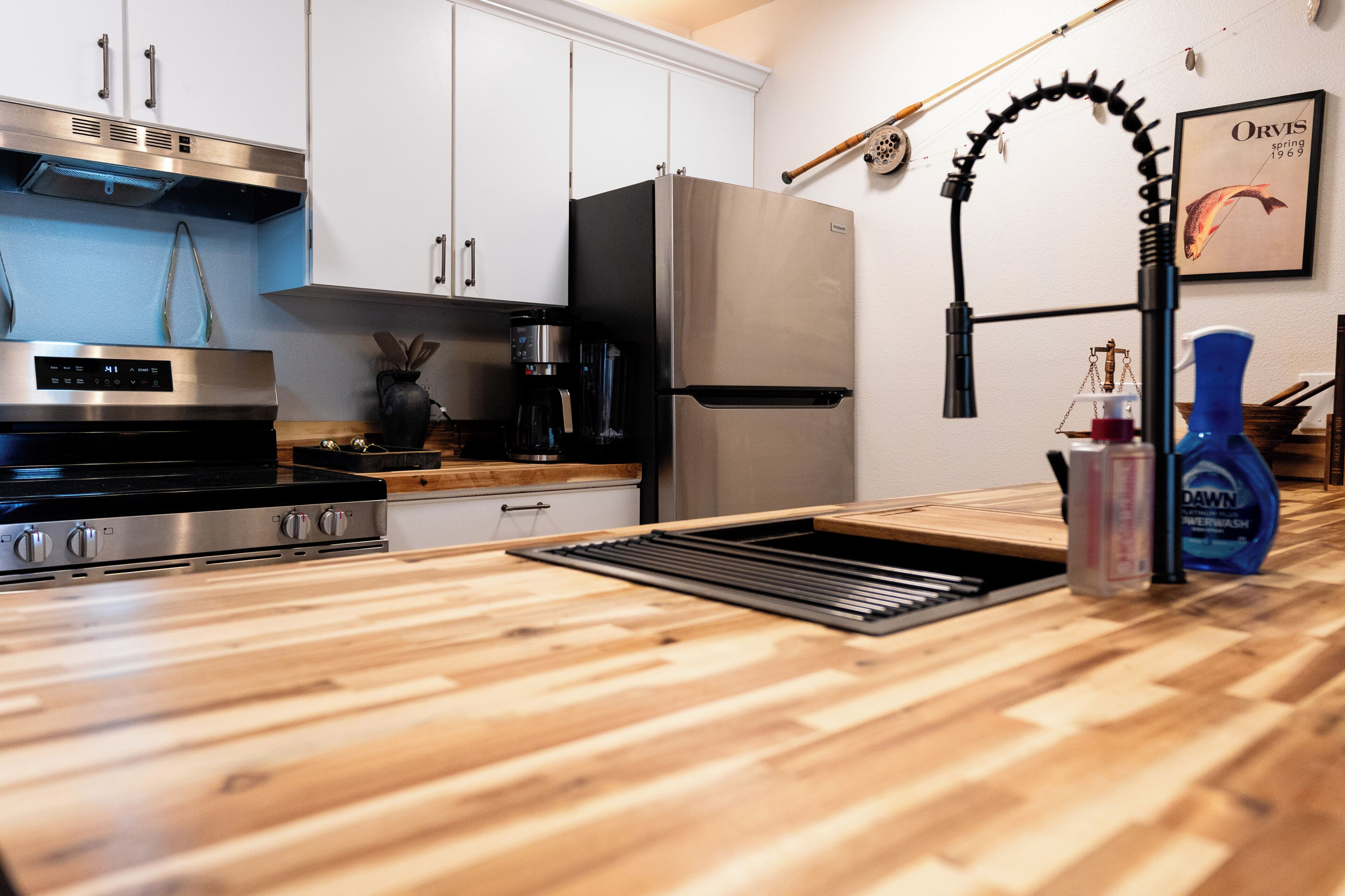 Una cocina moderna con electrodomésticos de acero inoxidable, encimera de madera y campana extractora de acero inoxidable.