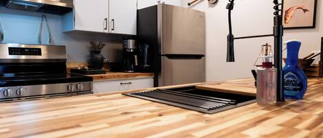 Una cocina moderna con electrodomésticos de acero inoxidable, encimera de madera y campana extractora de acero inoxidable.