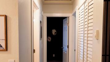 A narrow hallway with wooden flooring, white walls, and a ceiling light fixture.
