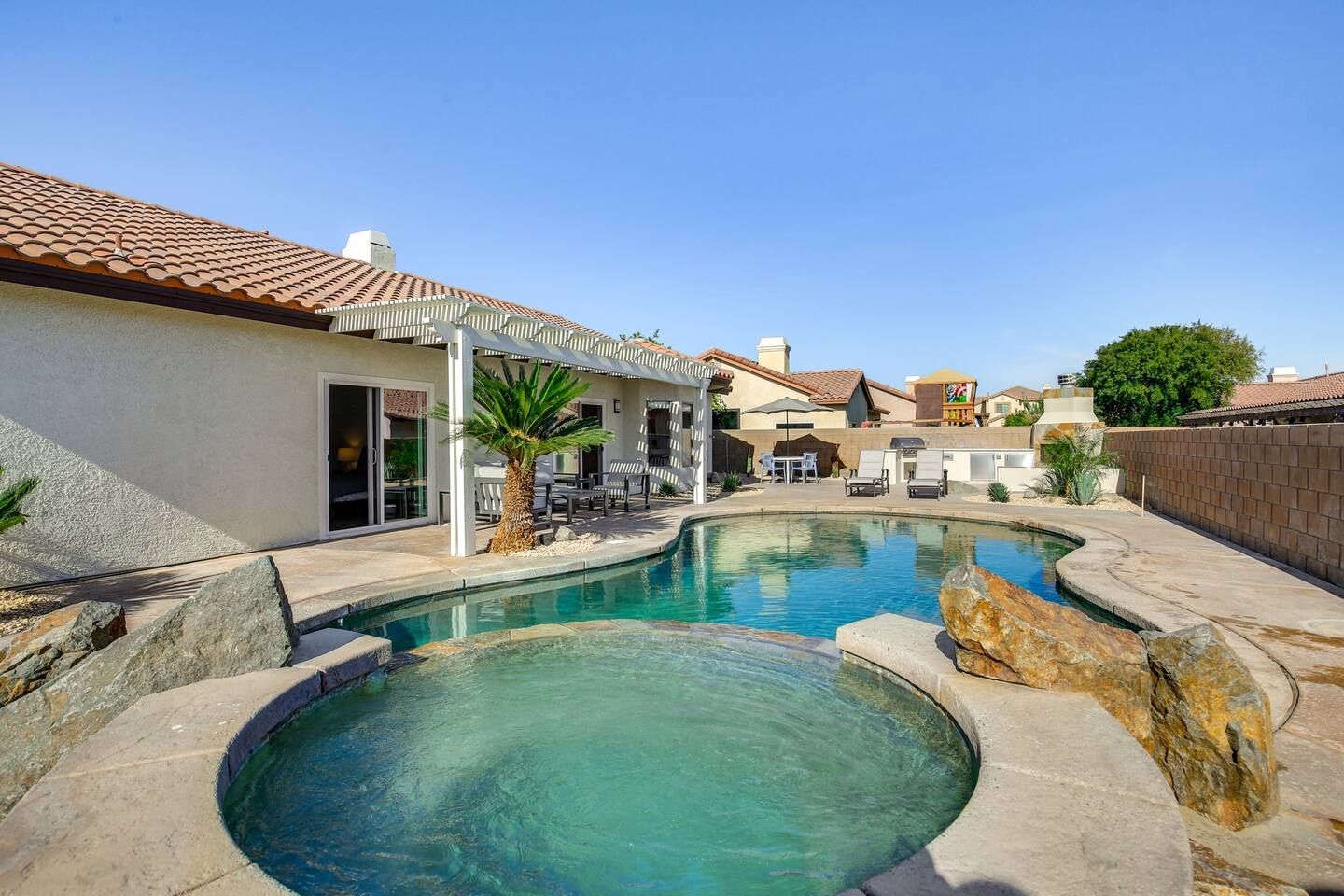 A residential area with two swimming pools, outdoor furniture, and a covered patio area.