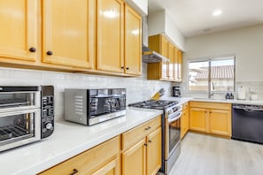 A modern kitchen with wooden cabinets, a built-in oven, a stove, and a dishwasher.