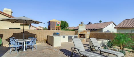An outdoor patio with a barbecue grill, a table with chairs, and a lounge area with chairs.