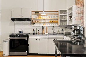 A modern kitchen with white cabinetry, a black stove, and a stainless steel oven.