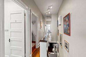 A hallway with white doors, a staircase, and artwork on the walls.